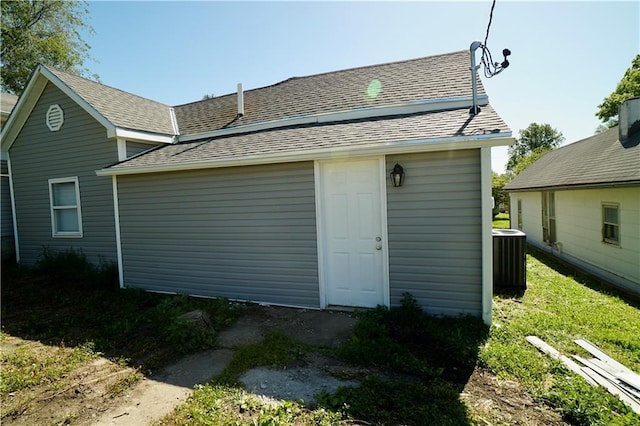 back of property featuring central AC unit and roof with shingles