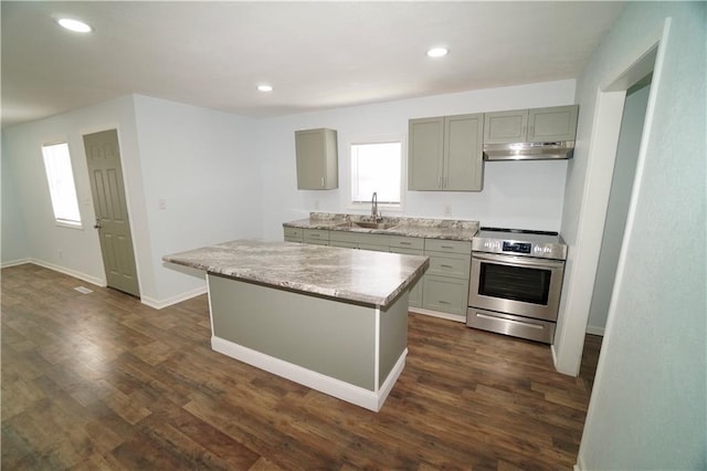 kitchen featuring electric stove, under cabinet range hood, gray cabinets, a sink, and dark wood-style floors