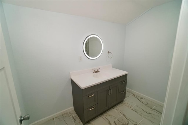 bathroom featuring marble look tiles, vanity, baseboards, and lofted ceiling