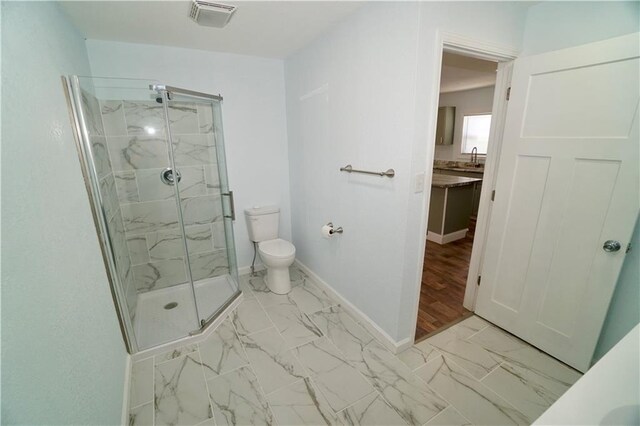 full bathroom with toilet, a marble finish shower, marble look tiles, baseboards, and vanity