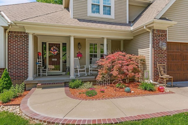 9008 N Hunter Ave, Kansas City, MO 64157 - property entrance featuring a porch, brick siding, a shingled roof, and a garage