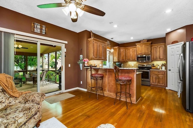 9008 N Hunter Ave, Kansas City, MO 64157 - kitchen featuring appliances with stainless steel finishes, ceiling fan, a peninsula, dark wood-style flooring, and recessed lighting