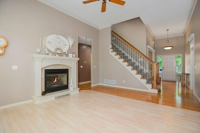 9008 N Hunter Ave, Kansas City, MO 64157 - unfurnished living room featuring wood finished floors, a ceiling fan, stairs, a premium fireplace, and crown molding