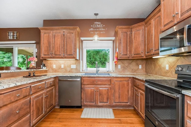 9008 N Hunter Ave, Kansas City, MO 64157 - kitchen with stainless steel appliances, light wood-style floors, decorative backsplash, and light stone countertops