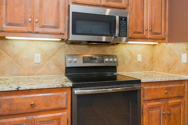 9008 N Hunter Ave, Kansas City, MO 64157 - kitchen featuring black range with electric stovetop, stainless steel microwave, decorative backsplash, and brown cabinetry