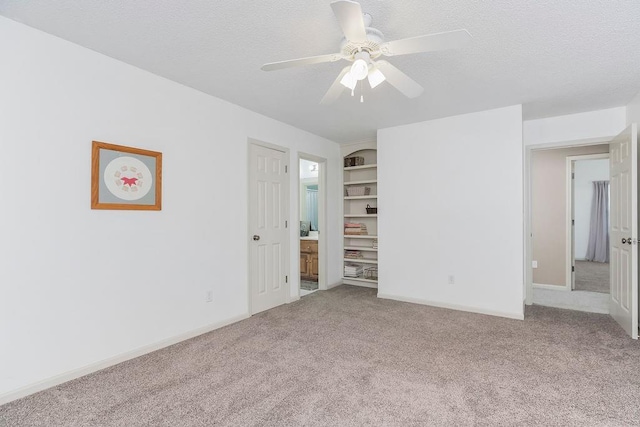 9008 N Hunter Ave, Kansas City, MO 64157 - empty room with carpet flooring, a ceiling fan, a textured ceiling, and built in features