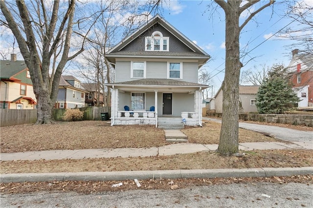 915 E 29th St, Kansas City, MO 64109 - american foursquare style home featuring a porch, fence, and a shingled roof