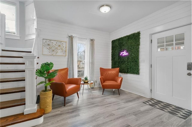 915 E 29th St, Kansas City, MO 64109 - living area with healthy amount of natural light, light wood-style flooring, wood walls, and stairway