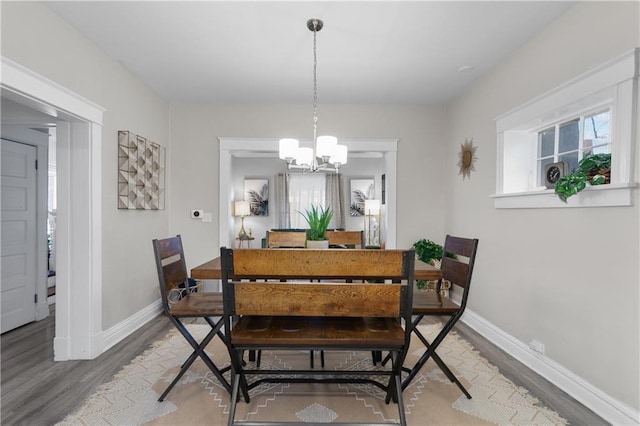 915 E 29th St, Kansas City, MO 64109 - dining area featuring wood finished floors, a chandelier, and baseboards