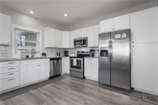 915 E 29th St, Kansas City, MO 64109 - kitchen with appliances with stainless steel finishes, a sink, backsplash, light stone counters, and recessed lighting