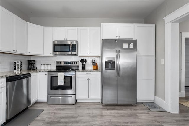 915 E 29th St, Kansas City, MO 64109 - kitchen featuring appliances with stainless steel finishes, light stone counters, and white cabinets