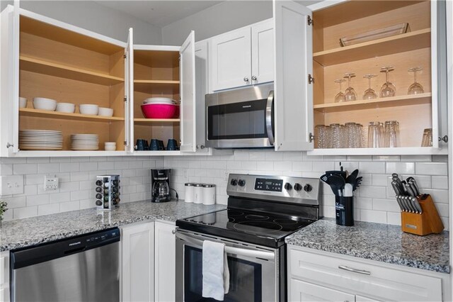 915 E 29th St, Kansas City, MO 64109 - kitchen with stainless steel appliances, open shelves, white cabinets, tasteful backsplash, and light stone counters