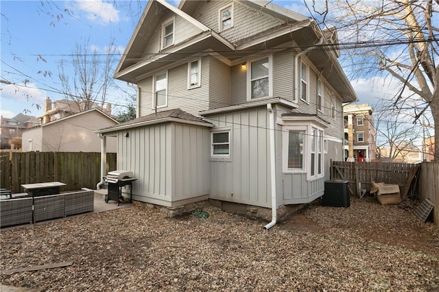 915 E 29th St, Kansas City, MO 64109 - view of home's exterior with a fenced backyard, board and batten siding, central air condition unit, and a patio
