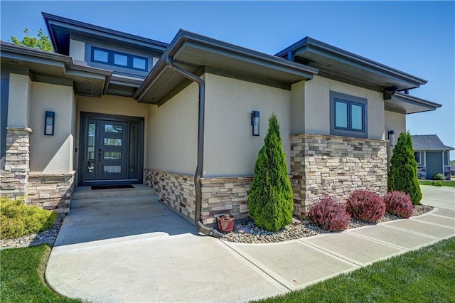 view of exterior entry featuring stone siding and stucco siding