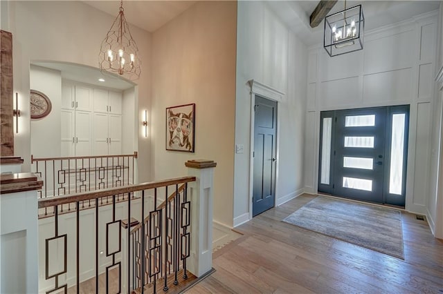 entryway featuring a chandelier, a high ceiling, wood finished floors, and baseboards