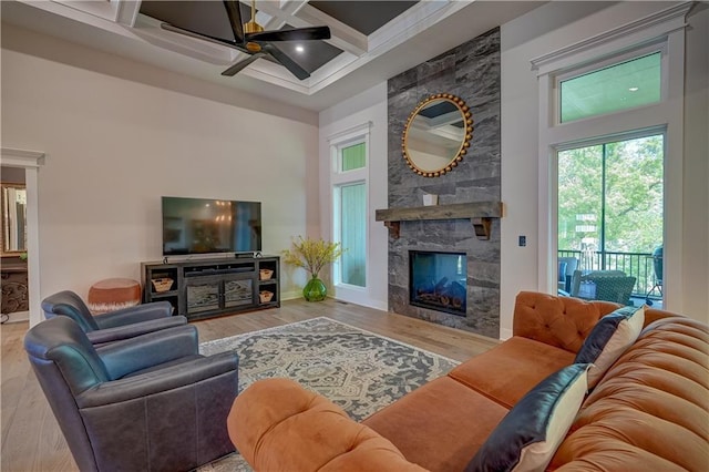 living area with a high ceiling, ceiling fan, wood finished floors, a premium fireplace, and beamed ceiling
