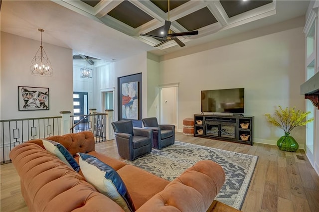 living room with a high ceiling, a chandelier, a ceiling fan, coffered ceiling, and hardwood / wood-style flooring