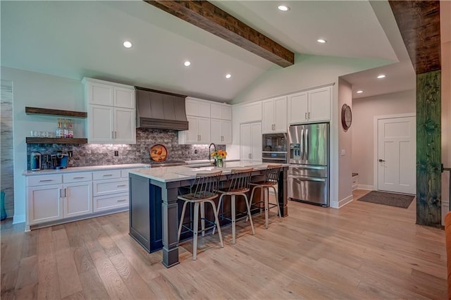 kitchen featuring stainless steel appliances, custom exhaust hood, white cabinets, a sink, and light wood-type flooring