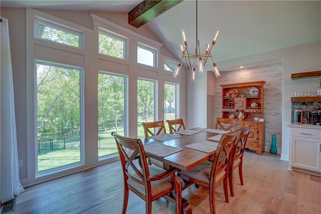 dining room featuring a chandelier, beamed ceiling, light wood-style floors, and high vaulted ceiling