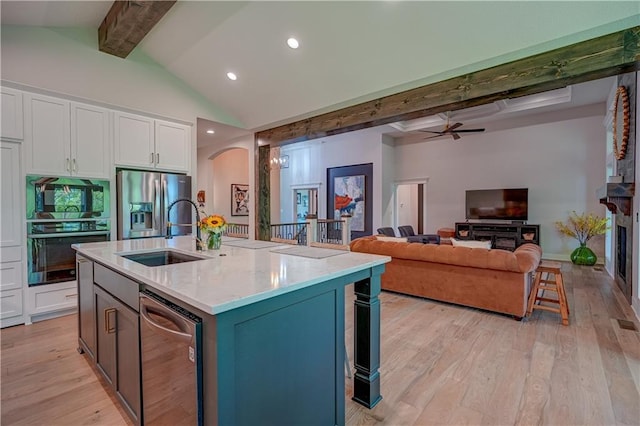 kitchen with stainless steel appliances, white cabinetry, a sink, a ceiling fan, and light wood-type flooring