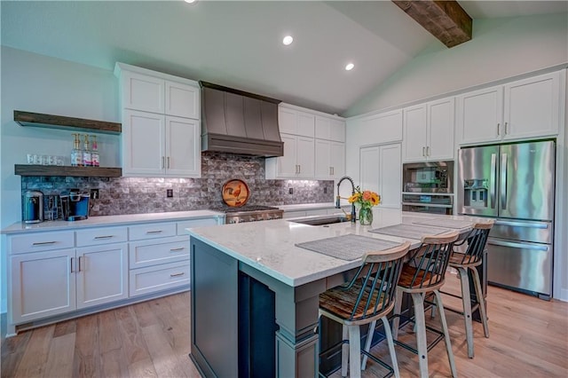 kitchen with stainless steel appliances, a sink, premium range hood, a breakfast bar area, and light wood-style flooring