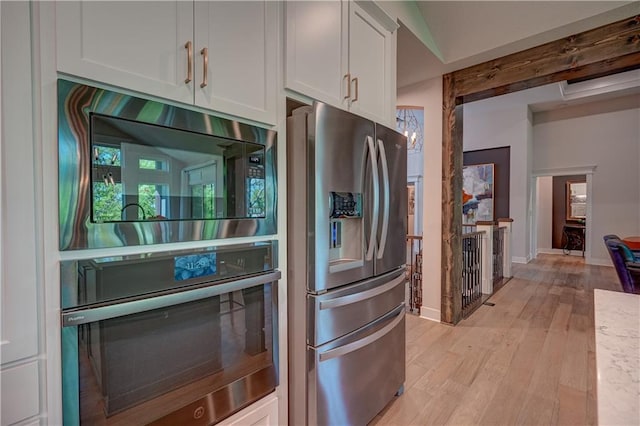 kitchen with stainless steel appliances, white cabinetry, light wood-style floors, baseboards, and light countertops