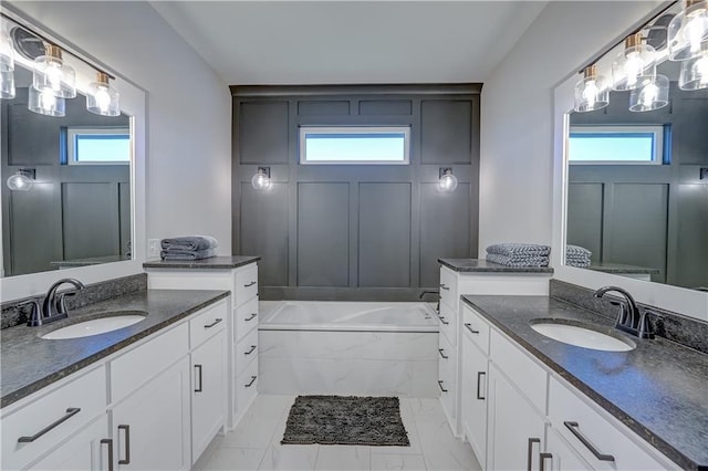 full bathroom featuring two vanities, plenty of natural light, and a garden tub
