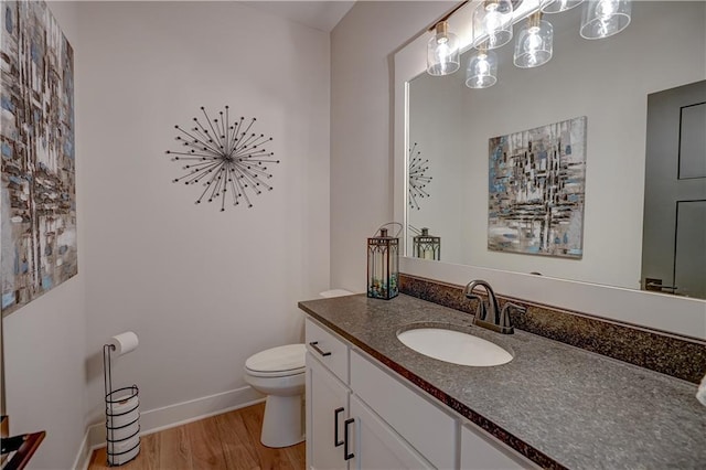 half bath with wood finished floors, toilet, vanity, baseboards, and a chandelier