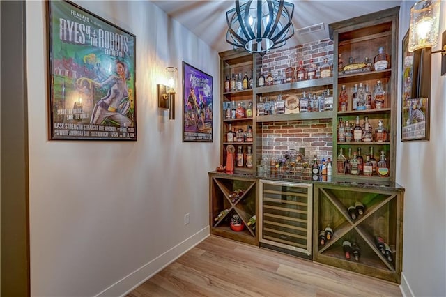 indoor dry bar featuring beverage cooler, baseboards, wood finished floors, and a chandelier