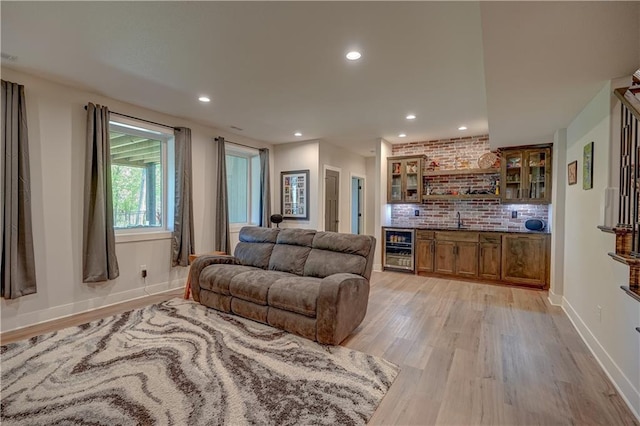 living area featuring beverage cooler, light wood-style floors, recessed lighting, and baseboards