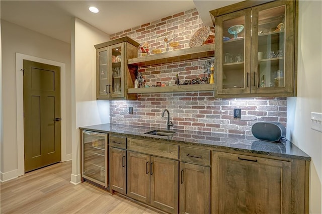 indoor wet bar with beverage cooler, light wood finished floors, and tasteful backsplash