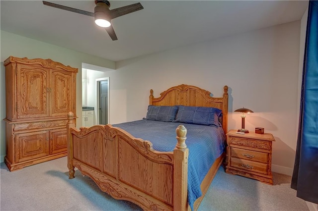 bedroom with light colored carpet, ensuite bathroom, and ceiling fan