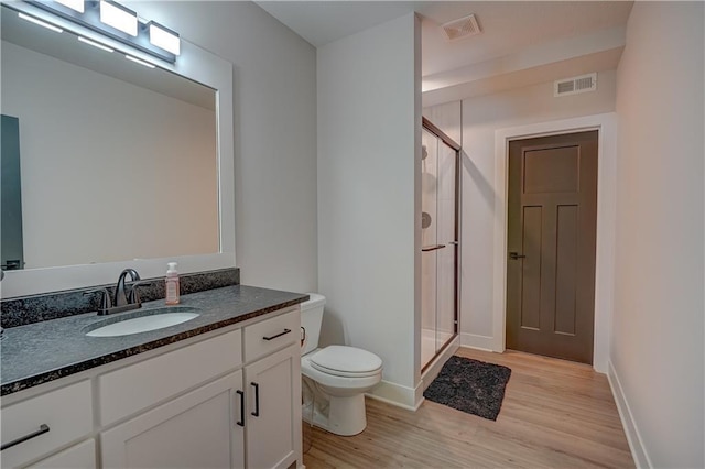 full bathroom featuring wood finished floors, toilet, a shower stall, vanity, and baseboards