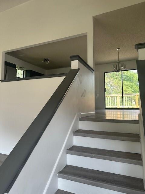7037 N Holmes St, Gladstone, MO 64118 - stairway featuring a chandelier and plenty of natural light