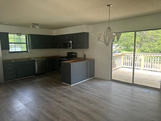 7037 N Holmes St, Gladstone, MO 64118 - kitchen with appliances with stainless steel finishes, a chandelier, a textured ceiling, wood finished floors, and dark cabinetry