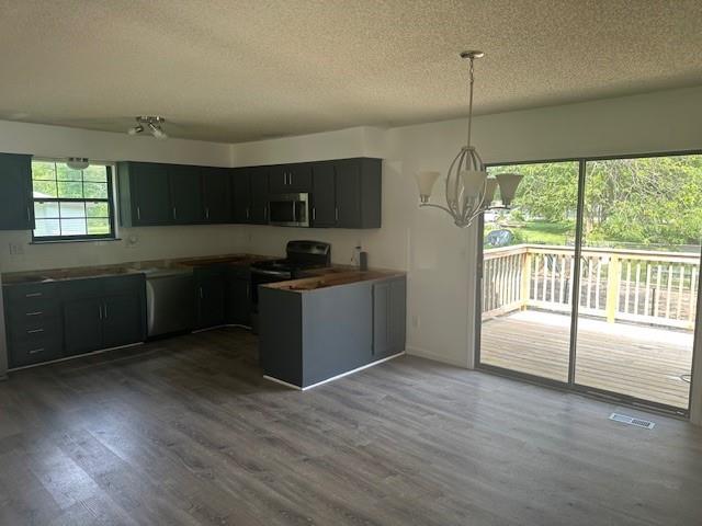 7037 N Holmes St, Gladstone, MO 64118 - kitchen with appliances with stainless steel finishes, a textured ceiling, a chandelier, wood finished floors, and dark cabinets