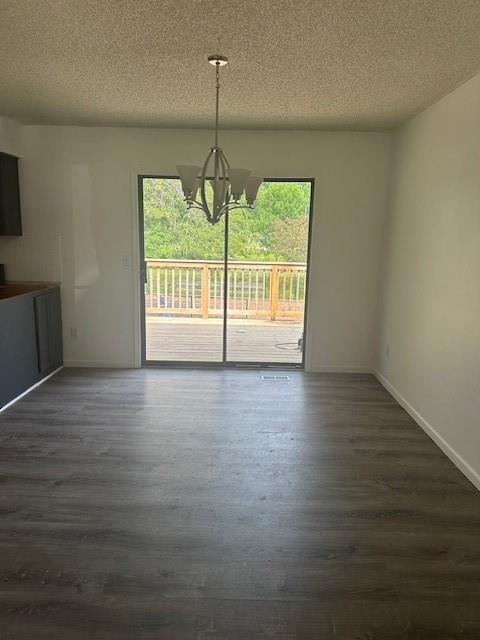 7037 N Holmes St, Gladstone, MO 64118 - unfurnished dining area with a chandelier, plenty of natural light, a textured ceiling, and dark wood finished floors