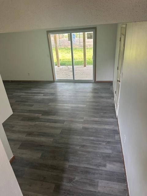 7037 N Holmes St, Gladstone, MO 64118 - empty room with dark wood finished floors, baseboards, and a textured ceiling