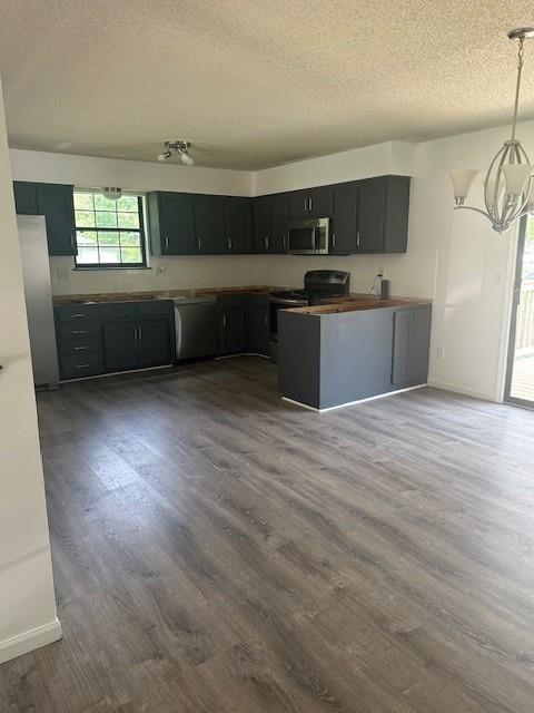 7037 N Holmes St, Gladstone, MO 64118 - kitchen featuring stainless steel appliances, a textured ceiling, a chandelier, dark wood-style floors, and baseboards