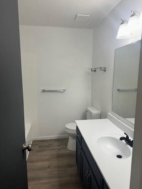 7037 N Holmes St, Gladstone, MO 64118 - full bath featuring toilet, vanity, wood finished floors, a textured ceiling, and baseboards