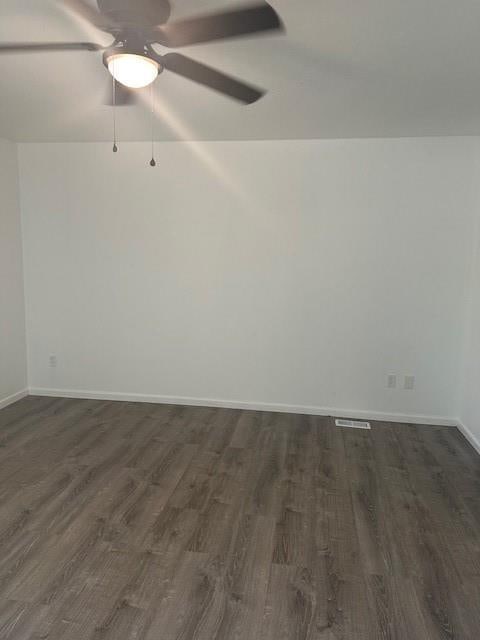 7037 N Holmes St, Gladstone, MO 64118 - unfurnished room featuring dark wood-style floors, ceiling fan, and baseboards