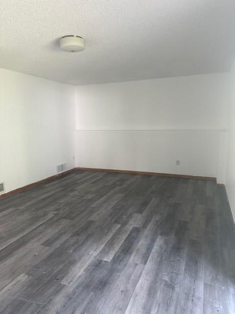 7037 N Holmes St, Gladstone, MO 64118 - empty room featuring dark wood-style flooring and baseboards