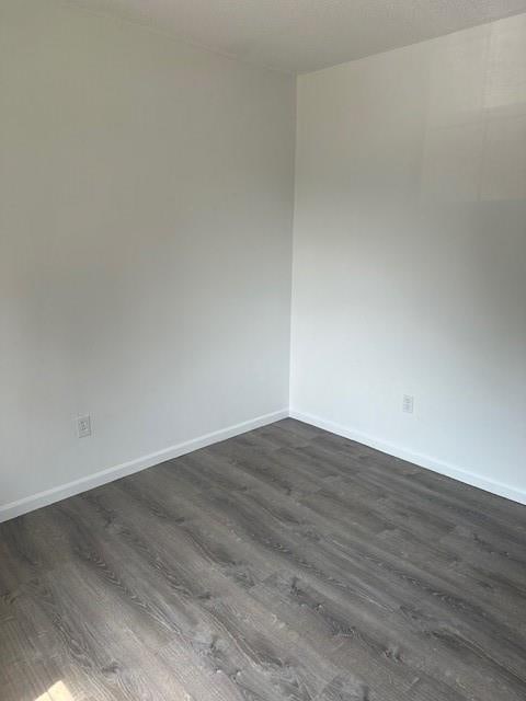 7037 N Holmes St, Gladstone, MO 64118 - spare room with dark wood-type flooring and baseboards