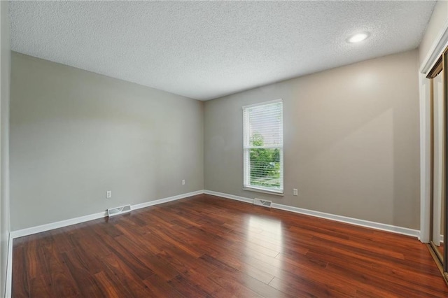 unfurnished room featuring a textured ceiling, wood finished floors, baseboards, and recessed lighting