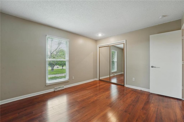unfurnished bedroom featuring wood-type flooring, a closet, a textured ceiling, baseboards, and recessed lighting