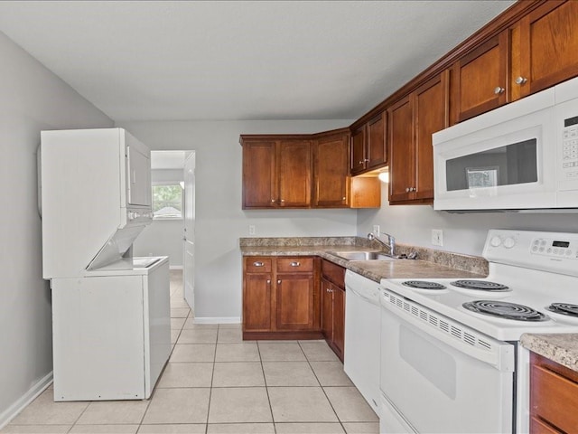 310-312 N 8th St, Leavenworth, KS 66048 - kitchen with white appliances, stacked washer and clothes dryer, a sink, light tile patterned floors, and brown cabinetry