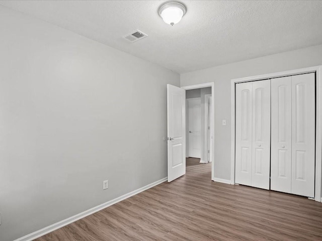 310-312 N 8th St, Leavenworth, KS 66048 - unfurnished bedroom featuring wood finished floors, baseboards, a closet, and a textured ceiling