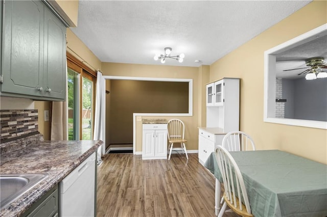 1608 SE Hillside Dr, Oak Grove, MO 64075 - kitchen with dishwasher, wood finished floors, a textured ceiling, a sink, and baseboards
