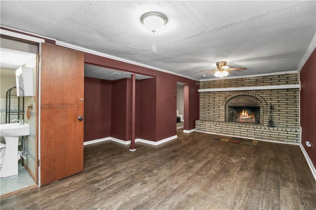 1608 SE Hillside Dr, Oak Grove, MO 64075 - unfurnished living room with ceiling fan, wood finished floors, a textured ceiling, a brick fireplace, and crown molding