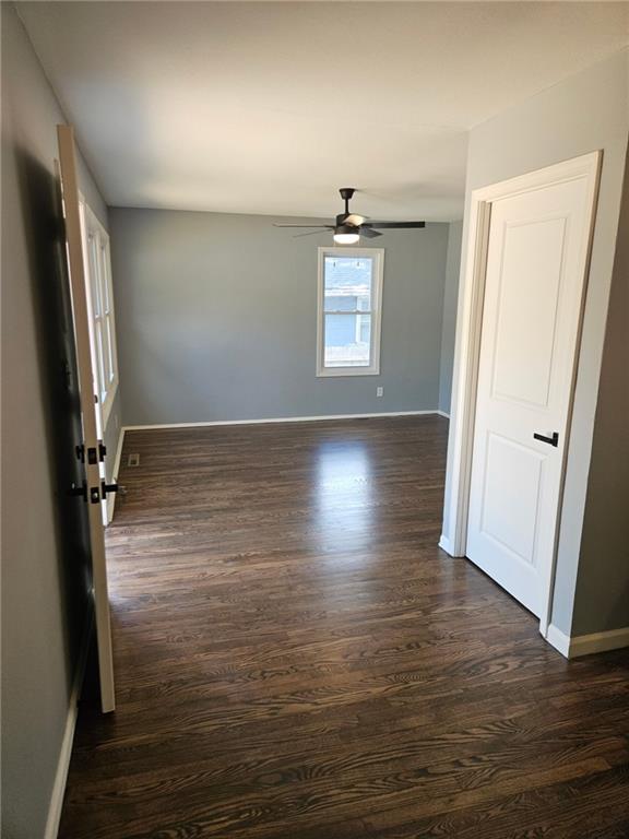 4715 E 45th St, Kansas City, MO 64130 - spare room with dark wood finished floors, a ceiling fan, and baseboards